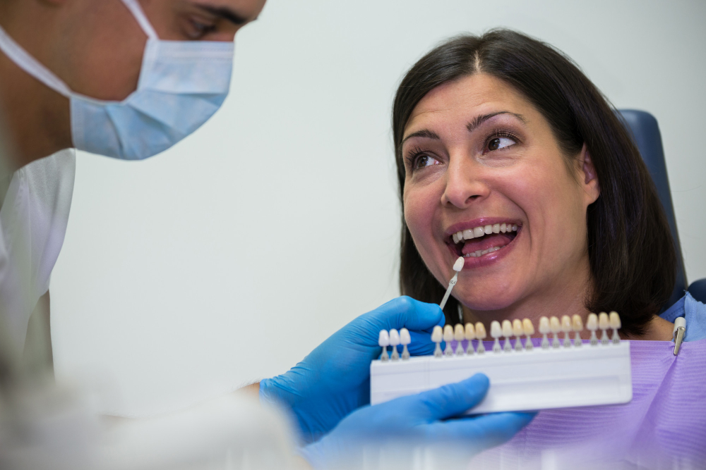 Dentist examining female patient with teeth shades Dentist examining female patient with teeth shades<br />